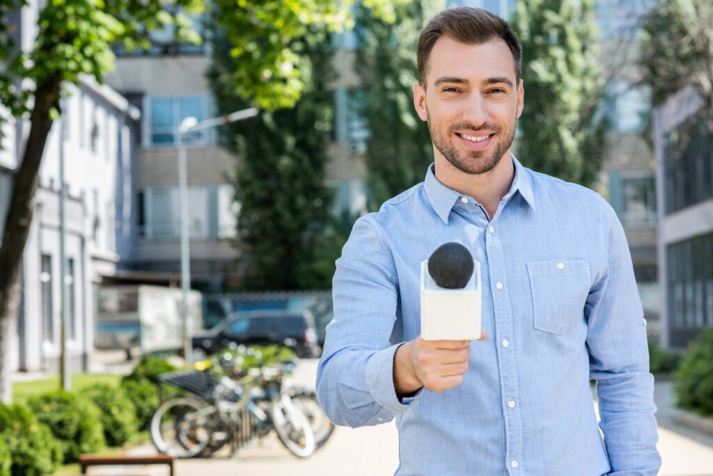 smiling male news reporter taking interview with microphone