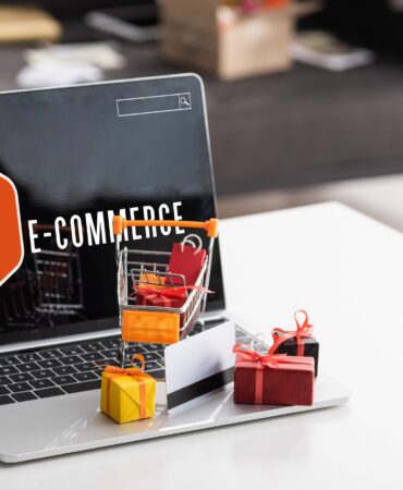 Toy gift boxes and credit card on laptop with e-commerce lettering on table