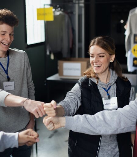 Group of volunteers at work in community charity donation center, fist bump
