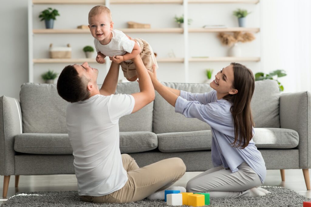 Young Parents Having Fun With Their Adorable Toddler Son At Home
