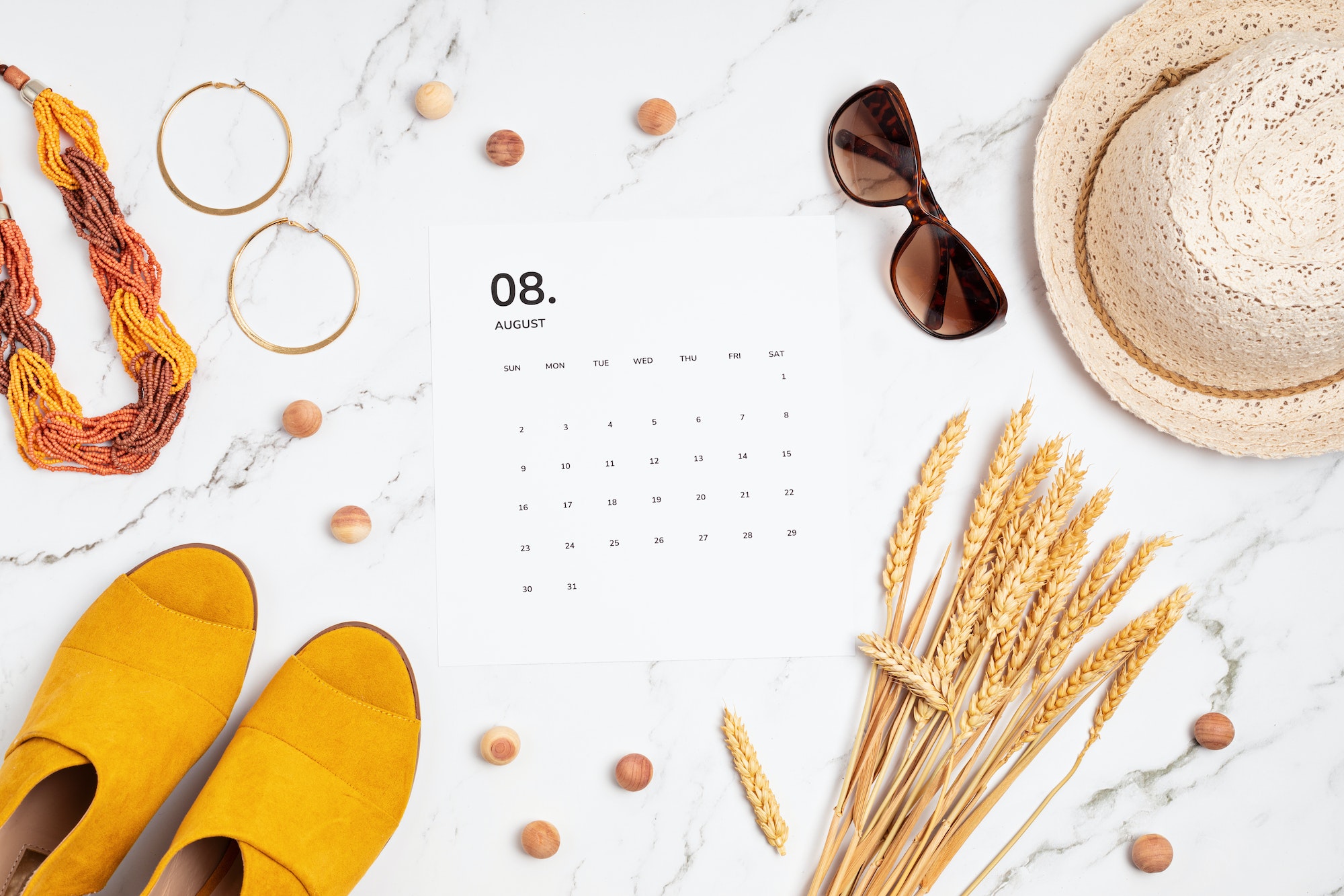 Flat lay with calendar for August with summer holidays fashion accessories