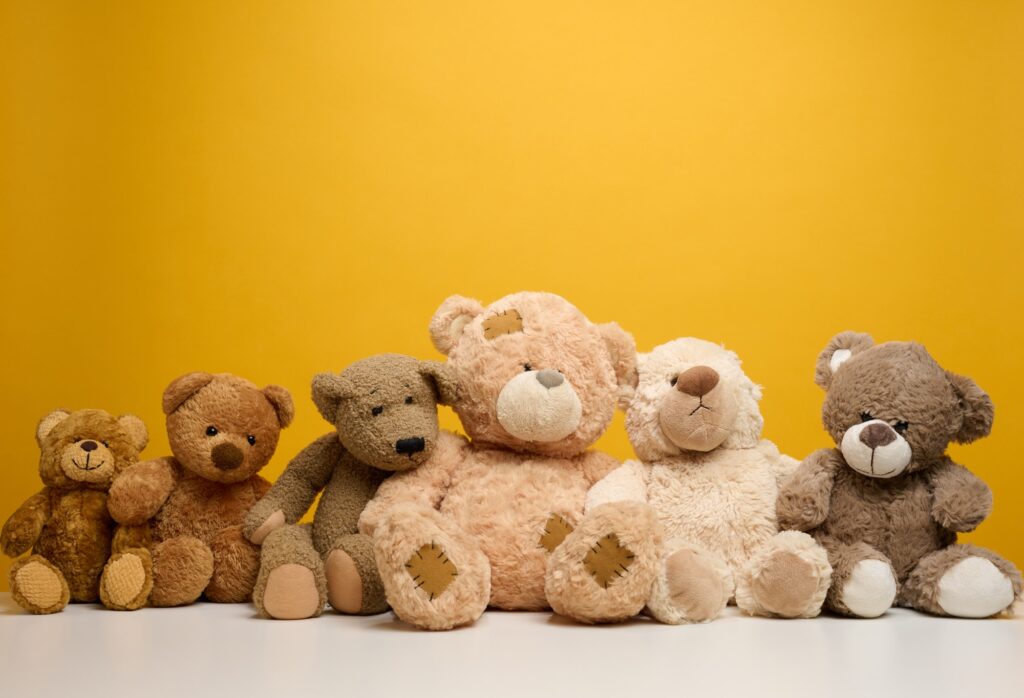 Group of cute brown teddy bears sit on yellow background, childrens toy