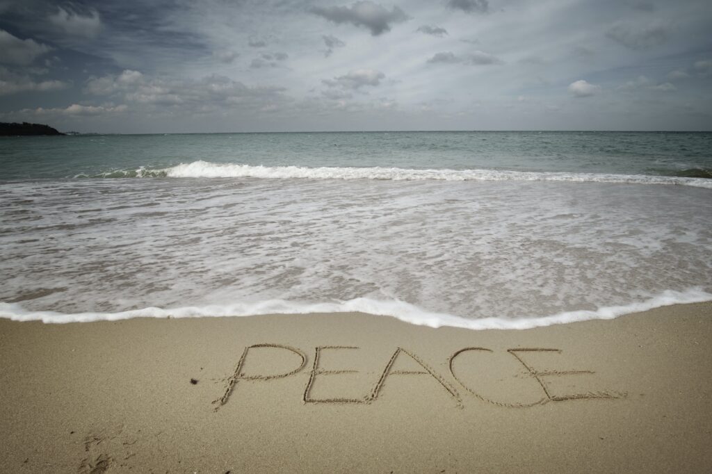 Peace word on sea sandy shore.