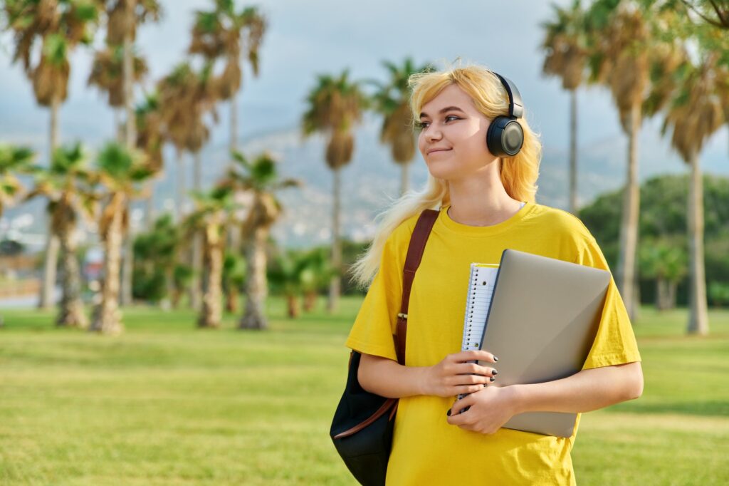 Outdoor portrait of teenage female student with laptop backpack.