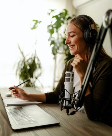 Young woman recording podcast using microphone. Radio host working from home.
