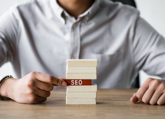 cropped view of seo manager holding wooden rectangle with lettering seo